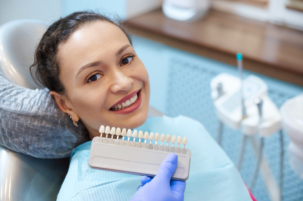 Dentist comparing tooth shades for natural-looking porcelain veneers during a cosmetic dentistry consultation.
