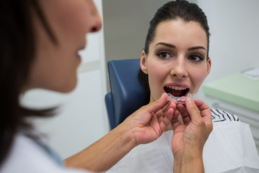 Dentist helping a patient try clear aligners during an Invisalign consultation.