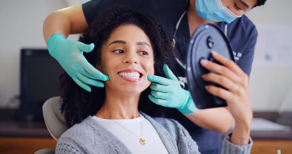 Patient reviewing her smile in a mirror during a comprehensive dental smile assessment.